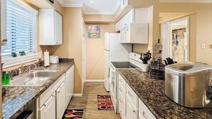 A kitchen with white cabinets, granite countertops, a stainless steel toaster, and a refrigerator. - Lakefront Action | Paddle • Pickle • Pool • Sunset (Montgomery)