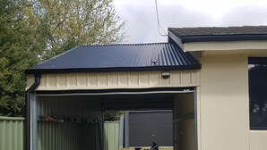 A garage with a bicycle parked inside, a closed garage door, and a green fence surrounding the area. - Aqua Vista  – Family friendly accommodation right in the heart of Yarrawonga. (Yarrawonga)