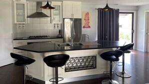 A modern kitchen with white cabinets, a large island with bar stools, stainless steel appliances, and pendant lighting. - Aqua Vista  – Family friendly accommodation right in the heart of Yarrawonga. (Yarrawonga)