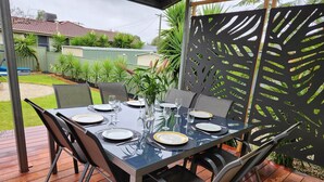 An outdoor dining area with a table set for four, surrounded by chairs and a decorative black partition. - Aqua Vista  – Family friendly accommodation right in the heart of Yarrawonga. (Yarrawonga)
