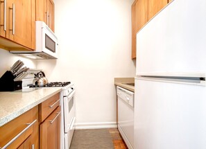 Une cuisine équipée de meubles en bois, d’un four à micro-ondes, d’une cuisinière, d’un lave-vaisselle et d’un réfrigérateur.