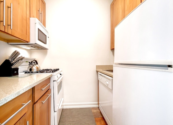 A kitchen with wooden cabinets, a microwave, a stove, a dishwasher, and a refrigerator.