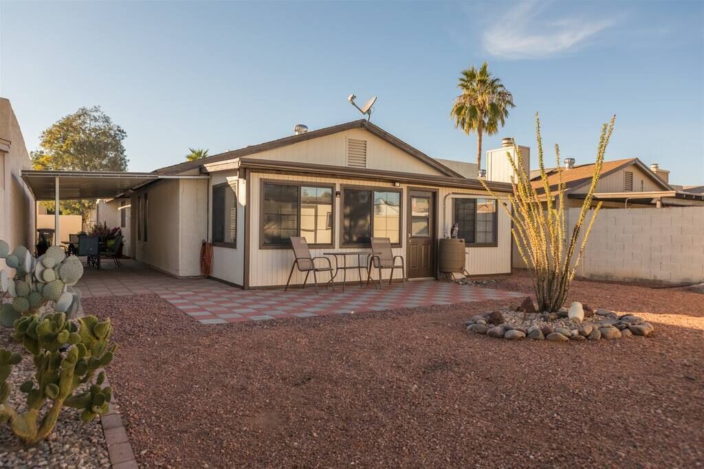 A single-story house with a covered patio, a small outdoor seating area, and a cactus plant in the foreground.