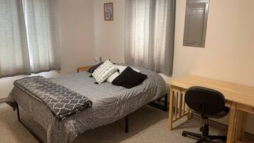 A bedroom with a bed, a desk, and a chair.