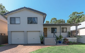 A two-story house with a garage, a front porch, and a staircase leading to the entrance.