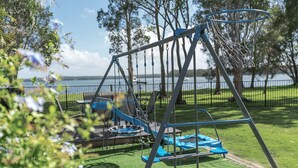 A playground with a swing set, slides, and a trampoline. - Getaway Lakefront environmental House with Kayaks Water Views (Chain Valley Bay)
