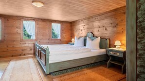 A wooden cabin bedroom with a bed, nightstands, and a window with curtains.