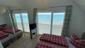 Une chambre avec un lit, une télévision et une vue sur la mer.