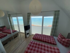 A room with a bed, a TV, and a view of the sea.