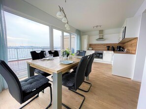 A modern kitchen with white cabinets, a wooden countertop, and a view of the water.