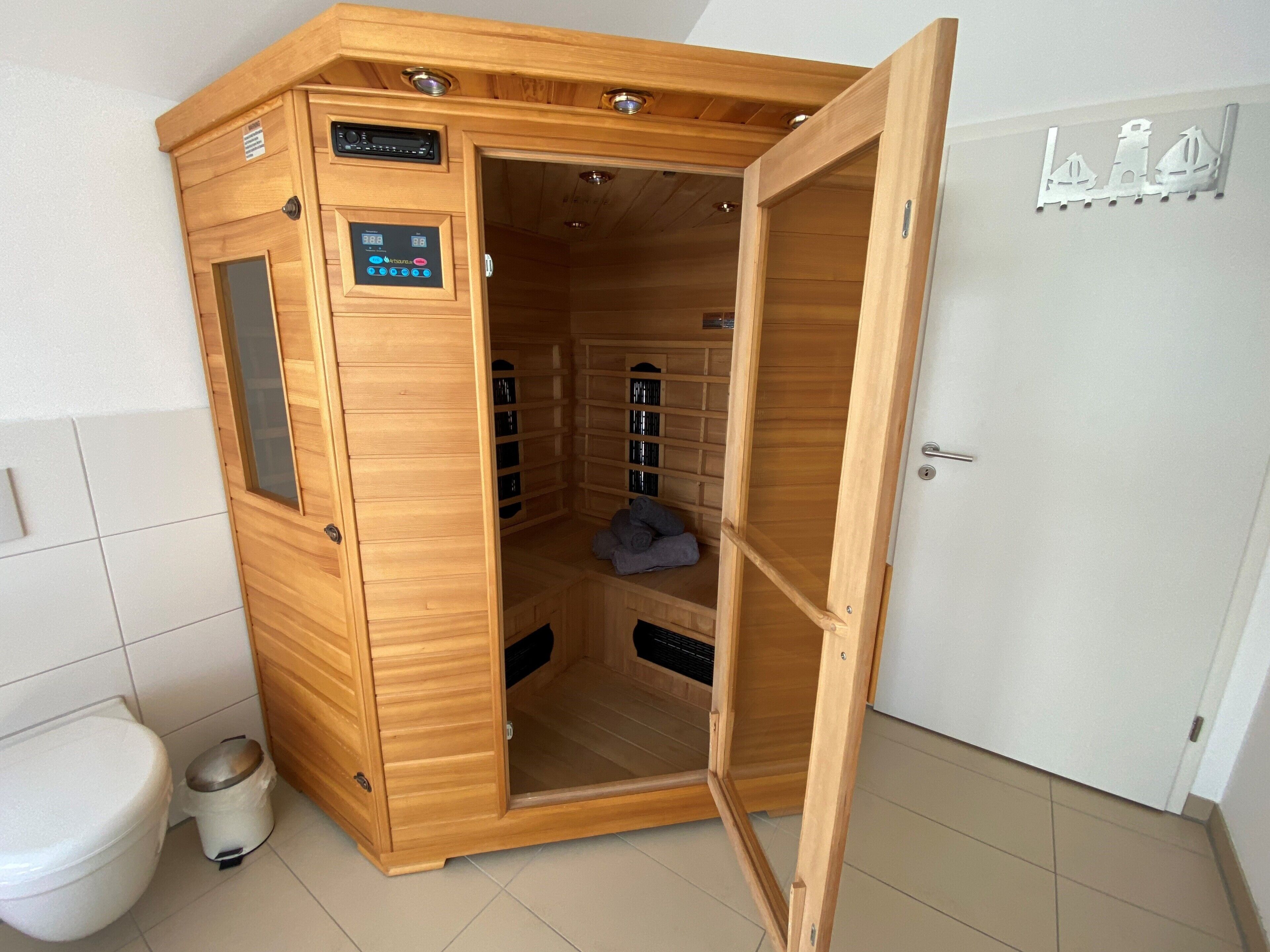 Un sauna avec une structure extérieure en bois, un panneau de commande et un sol carrelé.