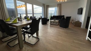 Een moderne woonkamer met een eethoek, grote ramen en uitzicht op de stad.