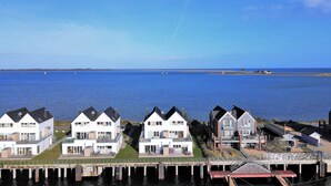 Een woongebied aan de kust met moderne huizen, een jachthaven en helder uitzicht op de zee.