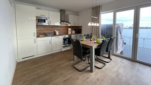 Een moderne keuken met witte kastjes, een houten aanrechtblad en een eethoek met een tafel gedekt voor vier personen.