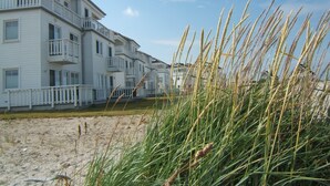Un hôtel situé en bord de mer, doté de nombreux balcons et donnant sur une plage de sable.