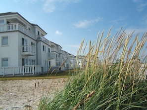 A beachfront hotel with multiple balconies and a sandy beach in the foreground.