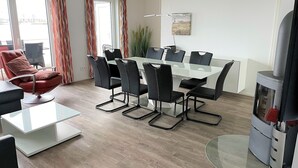 A modern dining area with a glass table, black chairs, a red chair, and a fireplace. - Vacation Home "Lootsen Hus by Seeblick Ferien" with Sea View (OstseeResort Olpenitz/ Kappeln)