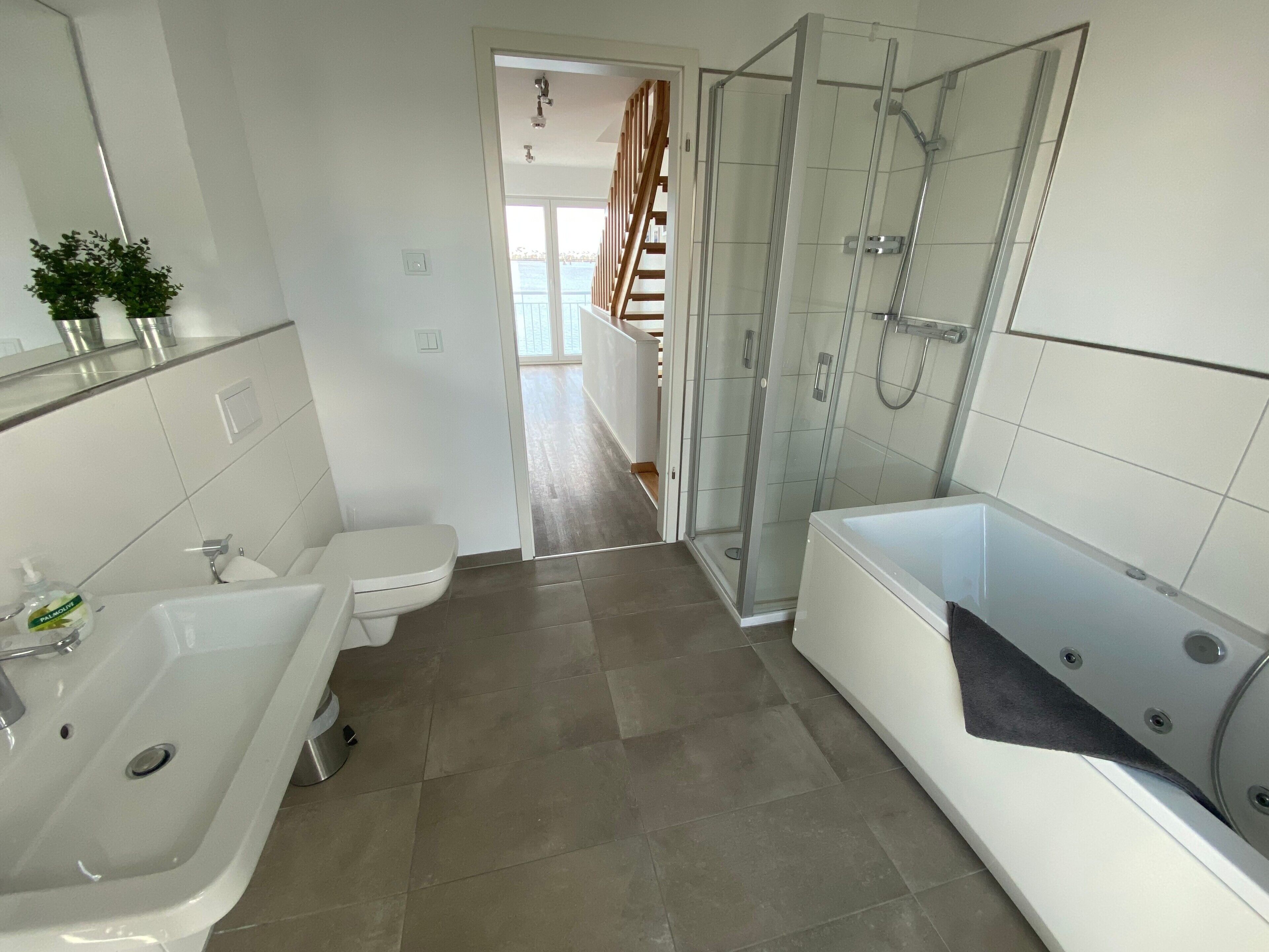 Een moderne badkamer met een bad, douche en toilet.