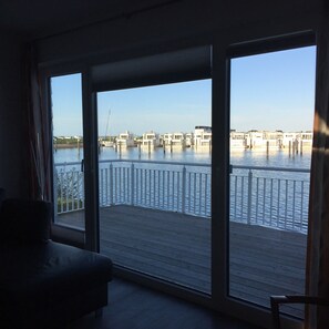 Una habitación con vistas a un cuerpo de agua, un balcón con barandilla y una silla.