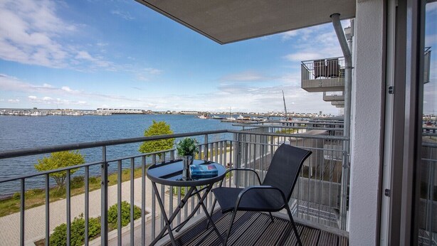 A balcony with a table and chairs, overlooking a body of water and a marina. - Holiday Apartment "Reeders Nest by Seeblick Ferien" with Sea View (OstseeResort Olpenitz)