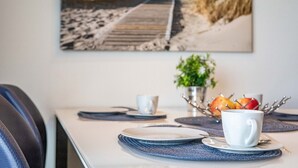 A dining table with plates, cups, and a fruit bowl. - Holiday Apartment "Reeders Nest by Seeblick Ferien" with Sea View (OstseeResort Olpenitz)