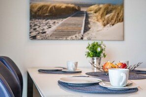 A dining table with plates, cups, and a fruit bowl.