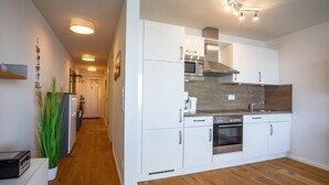A modern kitchen with white cabinetry, stainless steel appliances, and a wooden floor. - Holiday Apartment "Reeders Nest by Seeblick Ferien" with Sea View (OstseeResort Olpenitz)