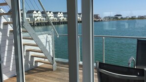 Une vue depuis un balcon donnant sur une étendue d’eau, avec des maisons en arrière-plan.