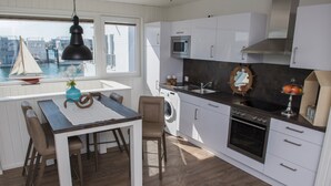 Une cuisine avec vue sur l’eau, un coin repas avec une table et des chaises, et un lave-linge.
