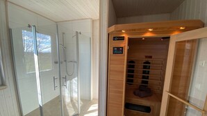 Un sauna équipé d’un panneau de commande, d’une porte en verre et d’un banc en bois.