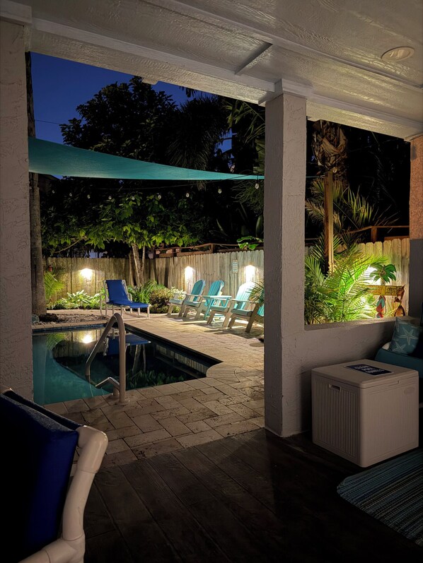 An outdoor pool area with lounge chairs and a covered seating area.