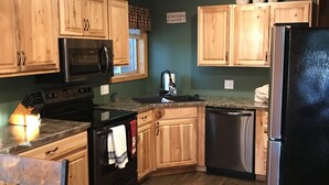 Una cocina con armarios de madera, microondas, estufa, lavavajillas y refrigerador.