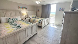 Une chambre avec deux lits, un ventilateur de plafond et une vue sur l’océan.