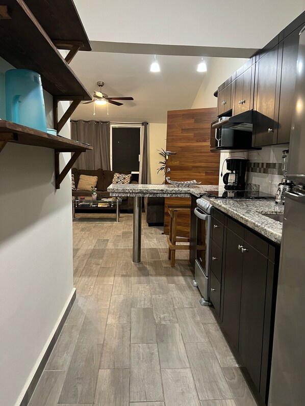 A modern kitchen with dark cabinets, a granite countertop, and a built-in microwave.