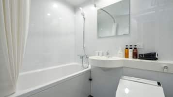 Ein modernes Badezimmer mit einer Badewanne, einem Waschbecken und einer Toilette. Auf dem Waschbecken befinden sich Pflegeprodukte.