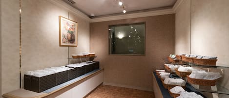 Un'area della reception di un hotel con un bancone che espone cesti di articoli da toilette, un quadro floreale appeso alla parete e una finestra che lascia entrare luce naturale.