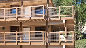 A multi-story building with balconies, wooden railings, and a clear view of the surrounding trees.