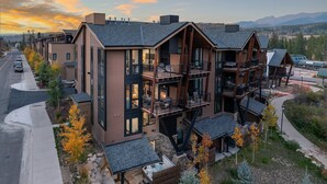 A modern multi-story building with balconies, large windows, and a hot tub area.