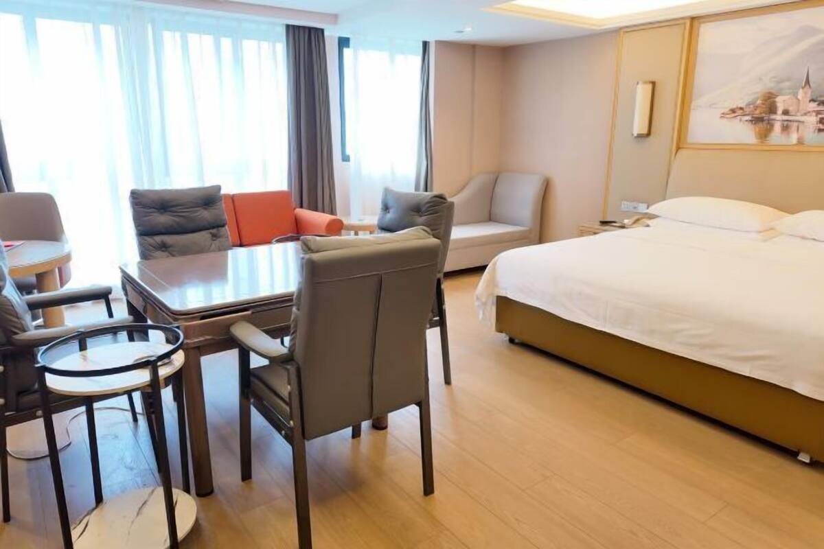 Ein Hotelzimmer mit einem Bett, einem Schreibtisch mit Stuhl, einer Couch und einem kleinen Tisch.