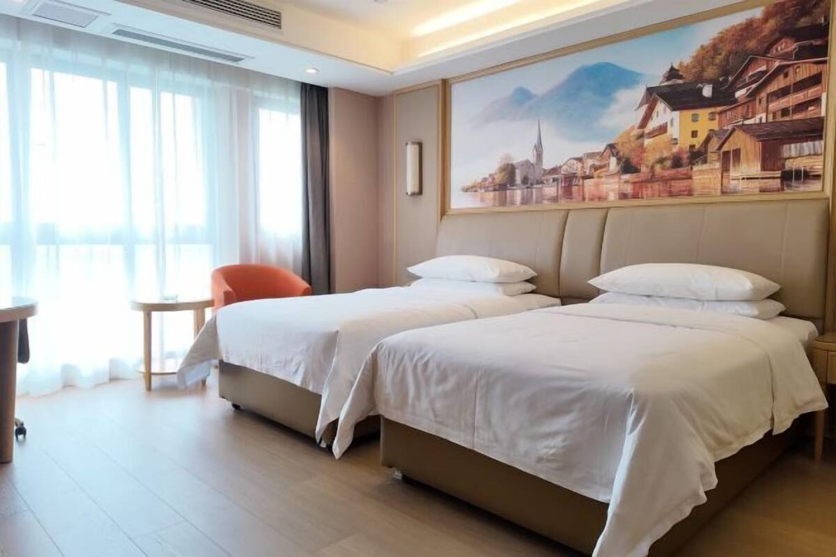 Ein Hotelzimmer mit zwei Betten, einem kleinen Tisch, einem Stuhl und einem Bild an der Wand.