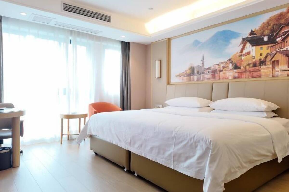 Ein Hotelzimmer mit einem großen Bett, einem Schreibtisch, einem Stuhl und einem Bild an der Wand.
