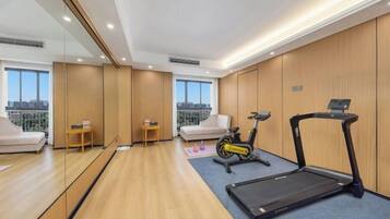 A hotel room with a treadmill, exercise bike, and a city view.