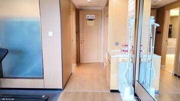 A hotel corridor with a reception desk, a glass door, and a visible elevator.