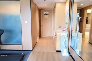 Un couloir d’hôtel avec un comptoir de réception, une porte vitrée et un ascenseur visible.