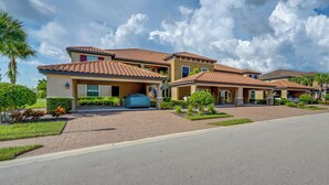 Uma área residencial com várias casas, telhados com azulejos, entradas de tijolo e jardins bem cuidados.