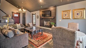 A living room with a fireplace, comfortable seating, and a chandelier. - Breezy Point Escape w/ Views, Dock & Fire Pit! (Breezy Point)