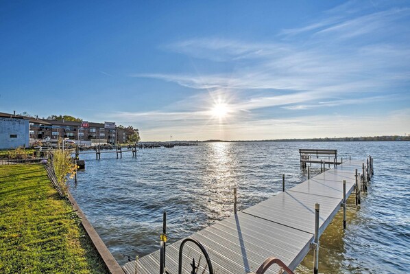 A dock extending into a body of water with a clear sky and a building on the left.
