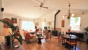 Un ampio soggiorno con camino, zona pranzo e ventilatore a soffitto.