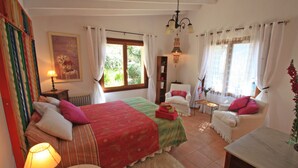 Una stanza con un letto, una sedia, un tavolo, una lampada e una finestra.
