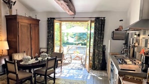 Un comedor con una mesa preparada para dos personas, un aparador de madera y vistas al exterior a través de un ventanal.